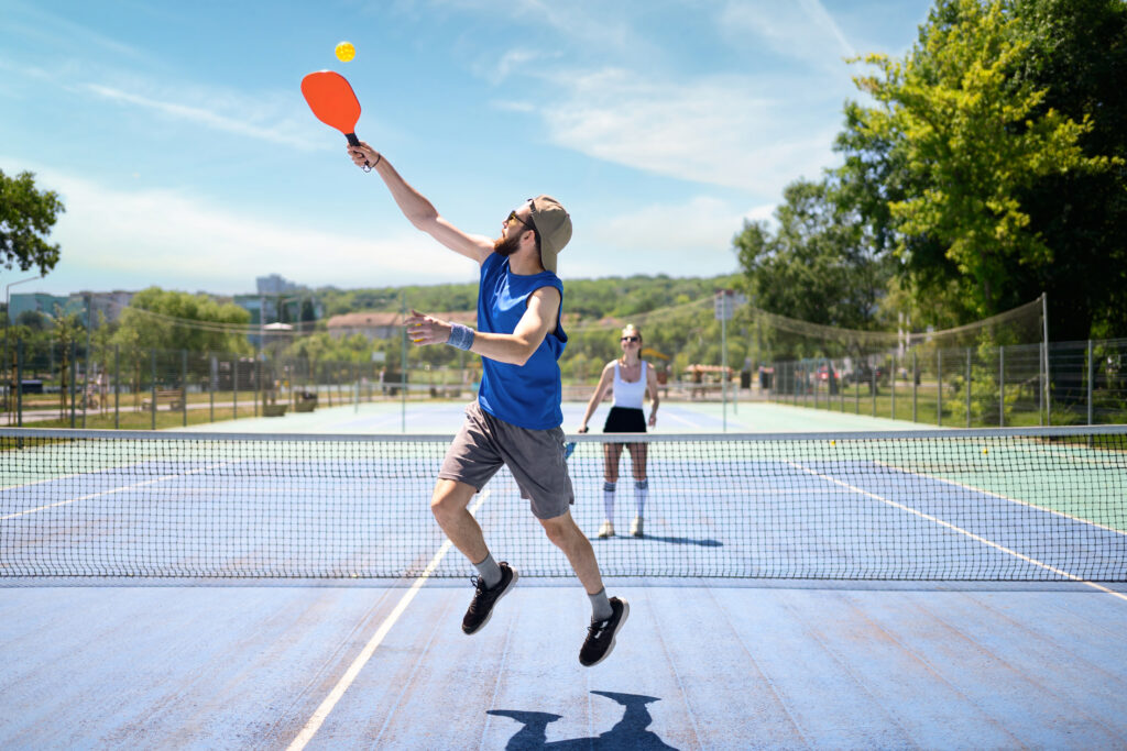 Couple playing pickleball outdoor at daylight. Outdoor sport leisure activity. Bright blue sky